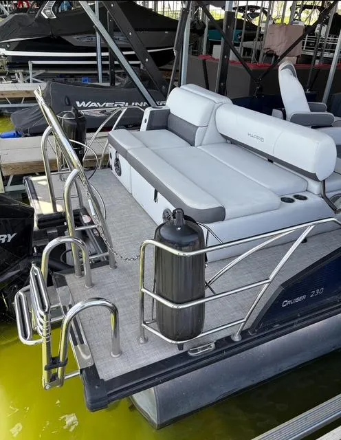 Slide: The Image of 2022 Harris Cruiser 230 pontoon boat docked, featuring spacious seating and modern design. - 13