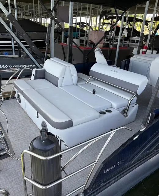 Slide: The Image of 2022 Harris Cruiser 230 boat with comfortable seating and sleek design in a marina setting. - 14