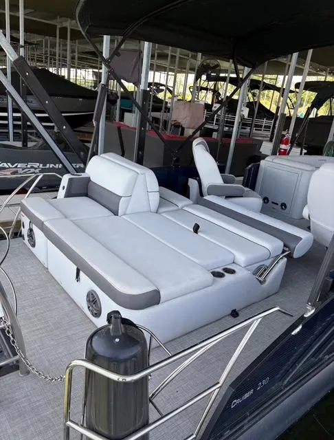 Slide: The Image of 2022 Harris Cruiser 230 boat with spacious seating and modern design in a marina setting. - 15