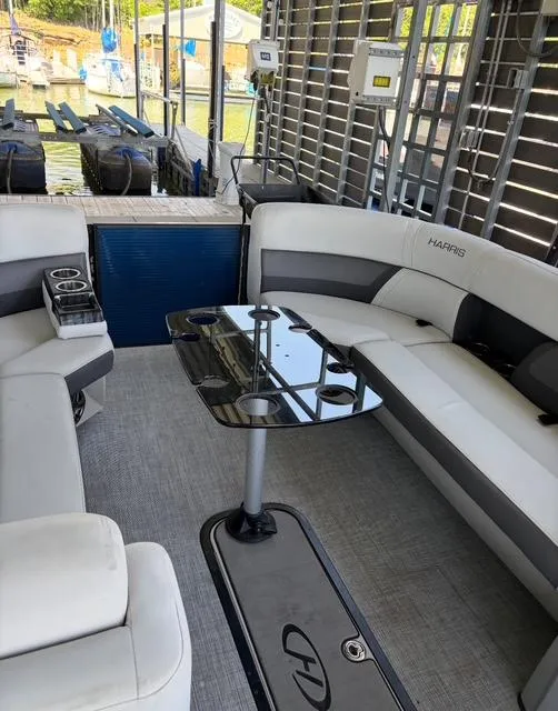 Slide: The Image of 2022 Harris Cruiser 230 interior with sleek seating and modern table, docked by the water. - 18