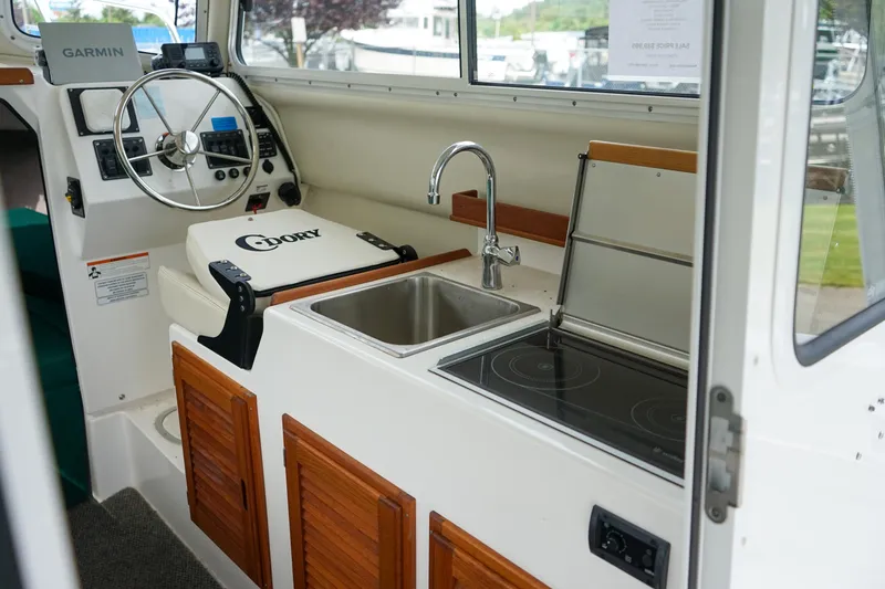 Slide: The Image of 2021 C-Dory 25' Cruiser interior with steering wheel, sink, and stove. - 12