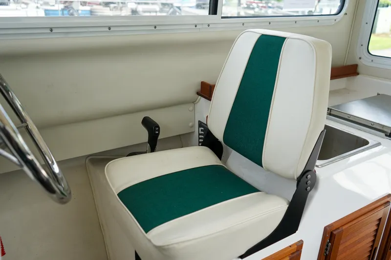 Slide: The Image of Captain's chair in 2021 C-Dory 25' Cruiser boat, featuring green and white upholstery. - 17