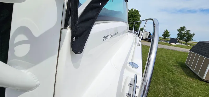 Slide: The Image of 2016 Boston Whaler 285 Conquest boat side view with railing, parked on grass. - 13