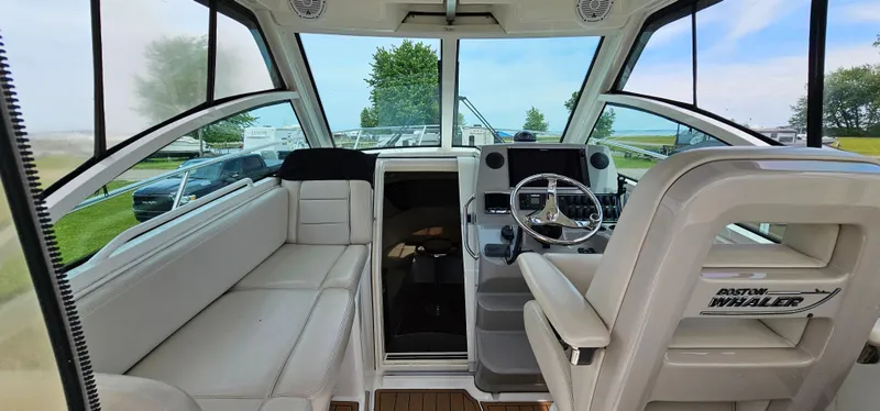 Slide: The Image of 2016 Boston Whaler 285 Conquest interior with helm, seating, and panoramic windows. - 18