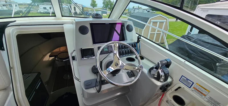 Slide: The Image of 2016 Boston Whaler 285 Conquest helm with steering wheel and navigation controls. - 24