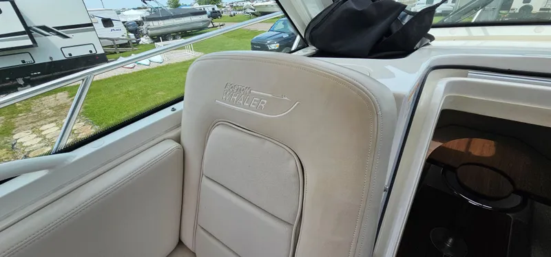 Slide: The Image of 2016 Boston Whaler 285 Conquest interior with beige seating and outdoor view. - 33