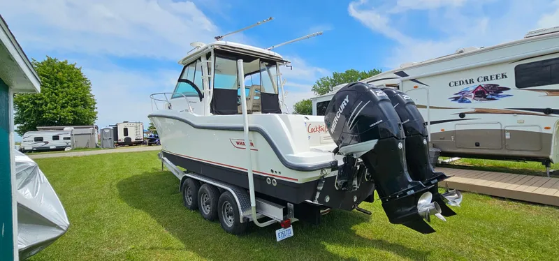 Slide: The Image of 2016 Boston Whaler 285 Conquest boat on trailer, parked on grass near RVs. - 4
