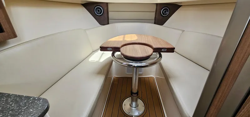 Slide: The Image of 2016 Boston Whaler 285 Conquest cabin interior with wood table and cushioned seating. - 40