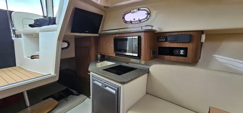 Slide: The Image of 2016 Boston Whaler 285 Conquest cabin with kitchenette, microwave, and seating area. - 42