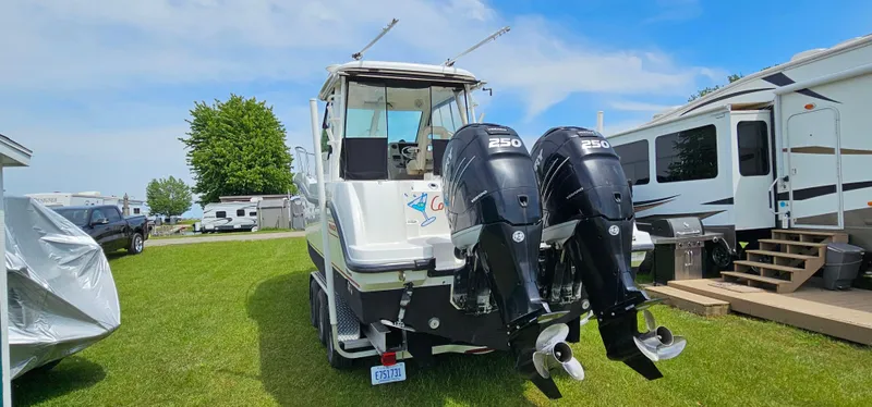 Slide: The Image of 2016 Boston Whaler 285 Conquest boat with dual engines, parked on grass near RVs. - 5