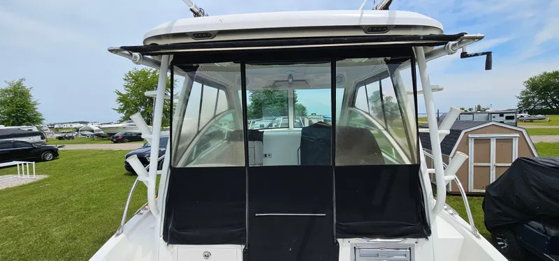 Slide: The Image of 2016 Boston Whaler 285 Conquest boat, rear view with enclosed cabin, parked on grass. - 9