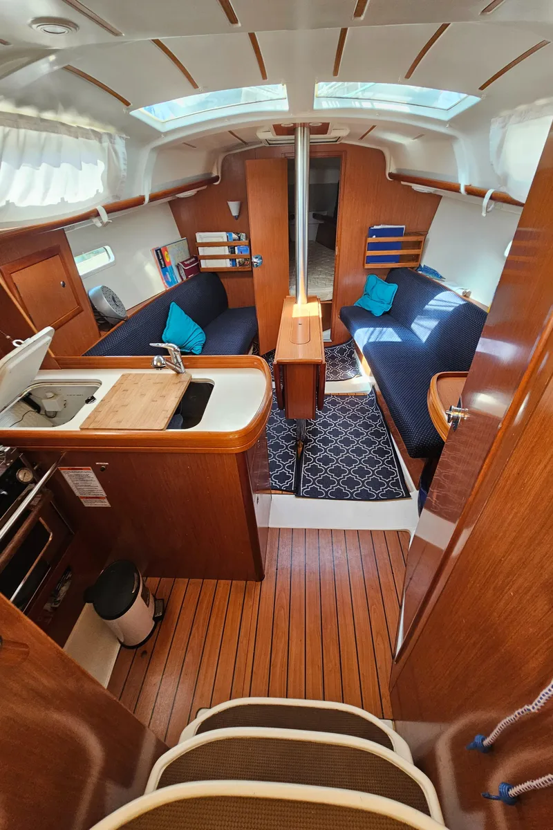 Slide: The Image of Interior of 2008 Beneteau 323 sailboat with wood finish, cozy seating, and compact kitchen area. - 14