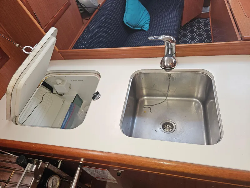 Slide: The Image of 2008 Beneteau 323 yacht kitchen sink and stove area with wooden cabinetry. - 18