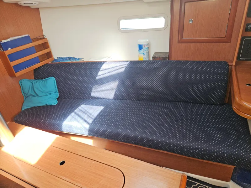 Slide: The Image of Interior of 2008 Beneteau 323 sailboat with blue cushioned seating and wooden cabinetry. - 19