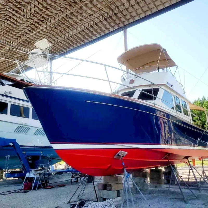 Slide: The Image of 2004 Sabreline 36 Flybridge Fast Trawler in dry dock, blue hull, red bottom, under shelter. - 1