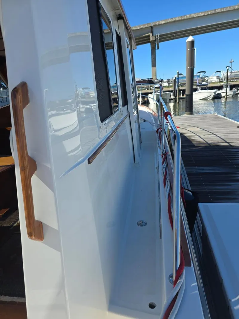 Slide: The Image of 2004 Sabreline 36 Flybridge Fast Trawler docked, showcasing side deck and marina view. - 11