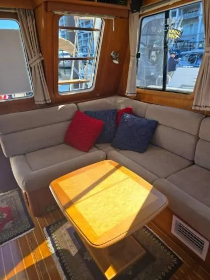 Slide: The Image of 2004 Sabreline 36 Flybridge Fast Trawler interior with cozy seating and wooden table. - 14