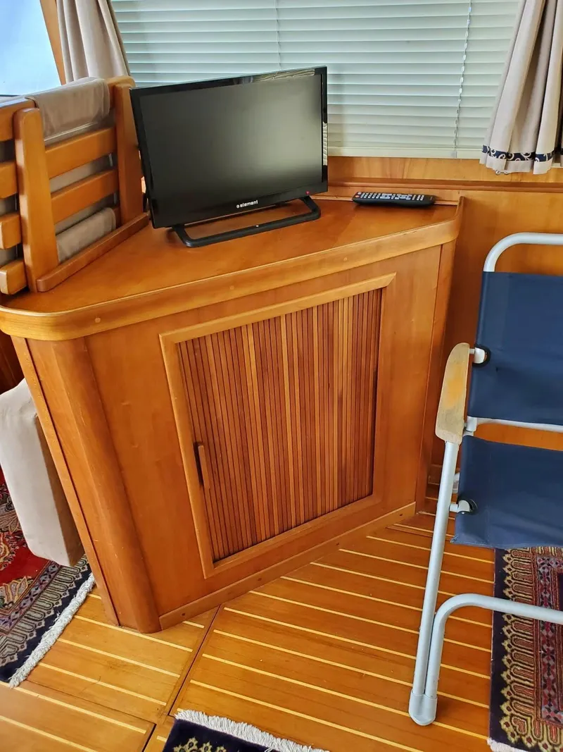 Slide: The Image of 2004 Sabreline 36 Flybridge Fast Trawler interior with TV, wooden cabinet, and chair. - 15
