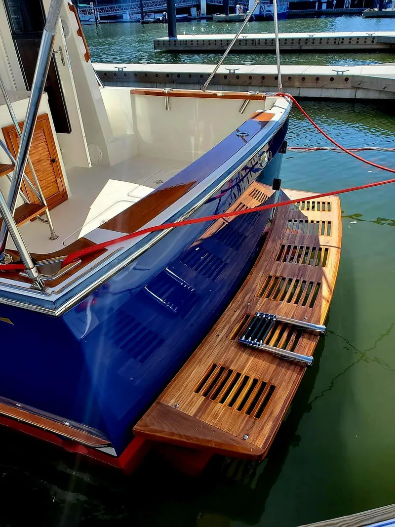 Slide: The Image of 2004 Sabreline 36 Flybridge Fast Trawler docked, featuring a wooden swim platform and blue hull. - 16