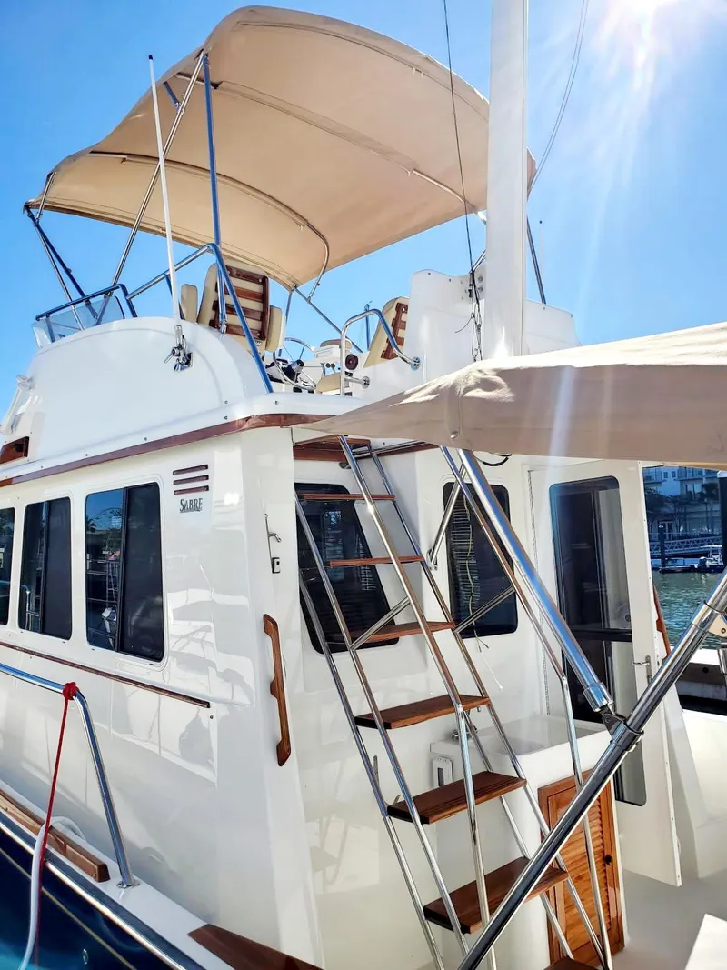 Slide: The Image of 2004 Sabreline 36 Flybridge Fast Trawler with sunshade, docked under clear blue sky. - 34