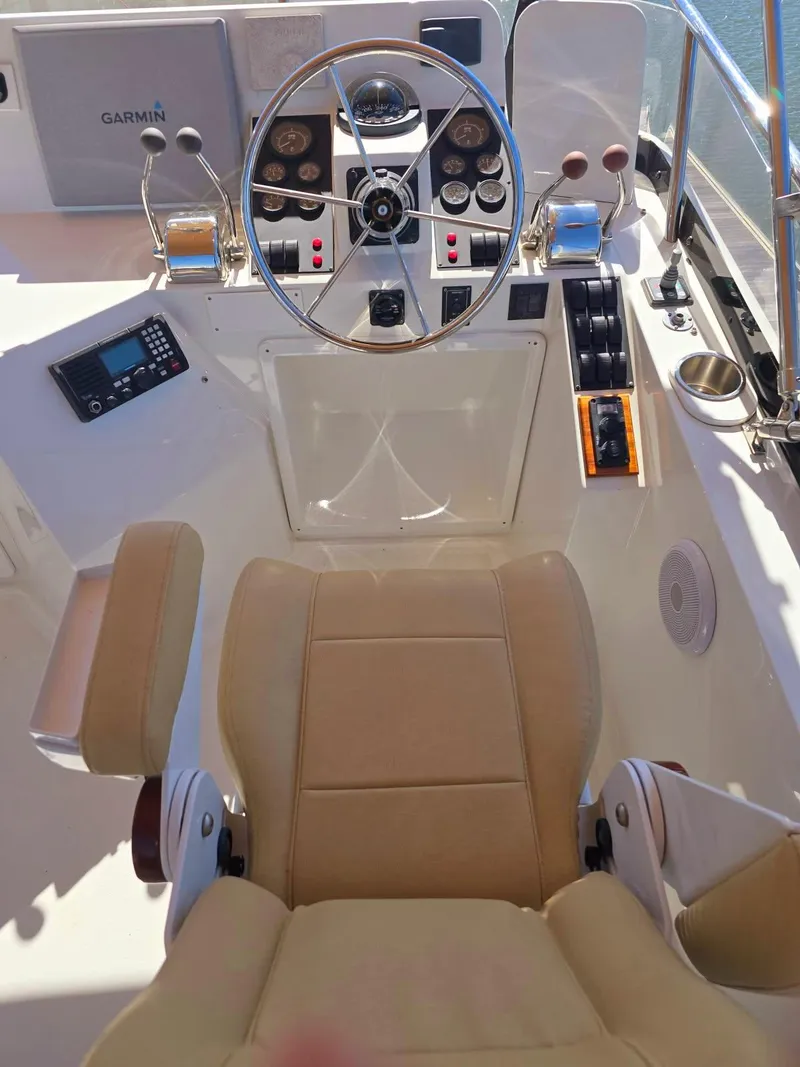 Slide: The Image of 2004 Sabreline 36 Flybridge Fast Trawler helm with beige seating and navigation controls. - 37