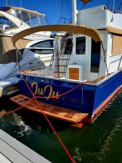 Slide: The Image of 2004 Sabreline 36 Flybridge Fast Trawler docked, featuring blue hull and wooden deck. - 4