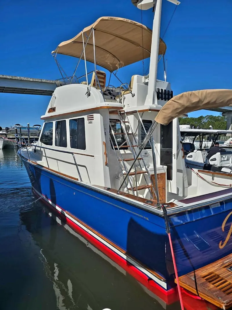 Slide: The Image of 2004 Sabreline 36 Flybridge Fast Trawler, blue hull, docked at marina under clear sky. - 7