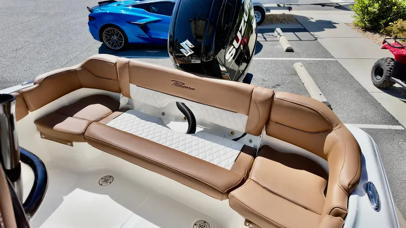 Slide: The Image of 2025 Pioneer 202 Islander boat with tan seating, parked near a blue sports car. - 7