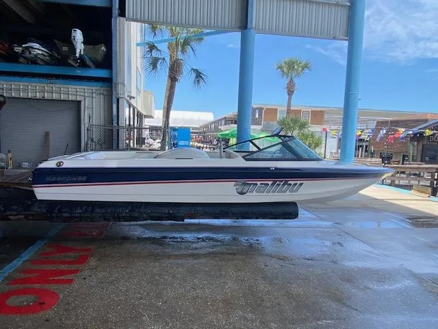 The Image of 1998 Malibu Response boat in marina, under blue sky, with palm trees in background. - 0