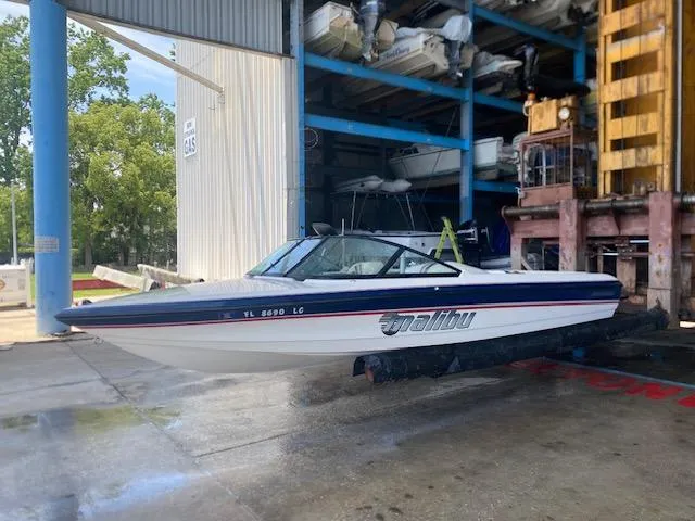 Slide: The Image of 1998 Malibu Response boat in storage facility, side view, white and blue design. - 1