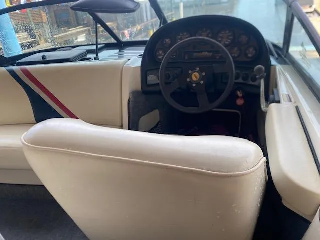 Slide: The Image of 1998 Malibu Response boat interior with steering wheel and dashboard, featuring white and striped seating. - 10