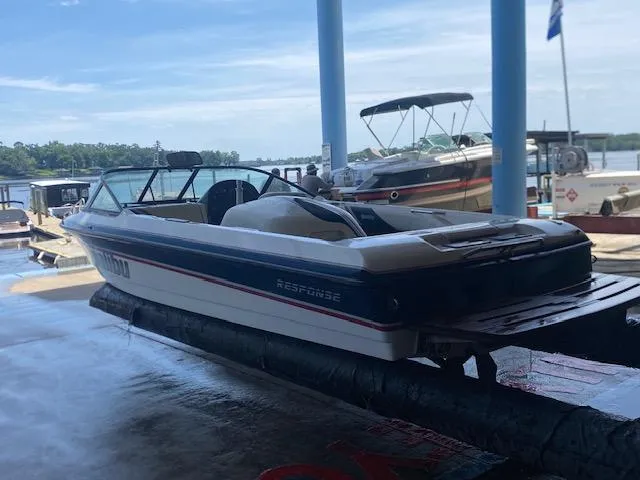 Slide: The Image of 1998 Malibu Response boat on lift at marina, with other boats in background. - 2
