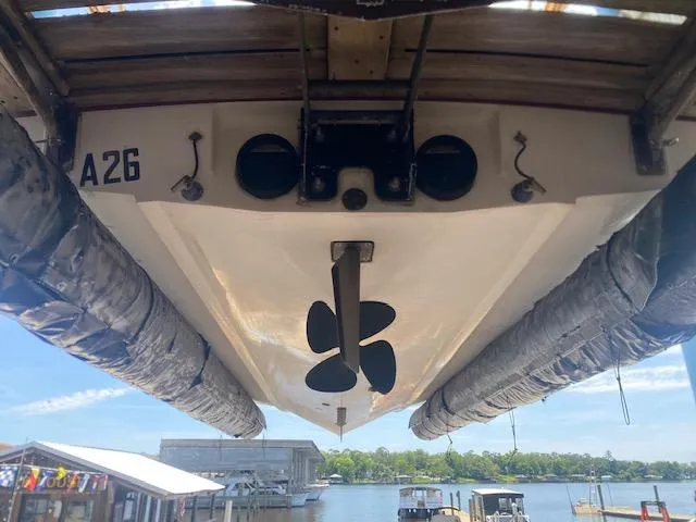 Slide: The Image of 1998 Malibu Response boat underside with propeller, docked by a scenic waterfront. - 22