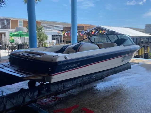 Slide: The Image of 1998 Malibu Response boat on lift, dockside with buildings and flags in background. - 4
