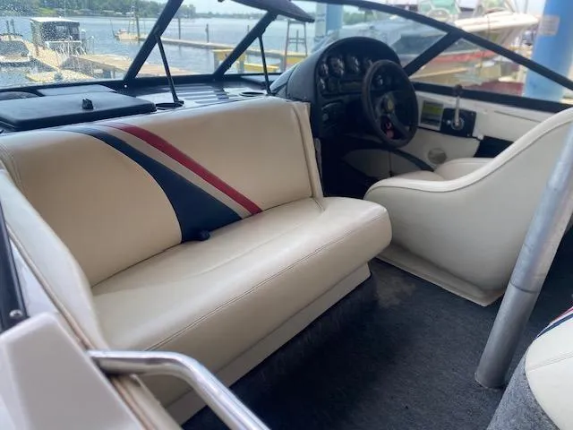 Slide: The Image of 1998 Malibu Response boat interior with white seating and dashboard, docked by the water. - 6