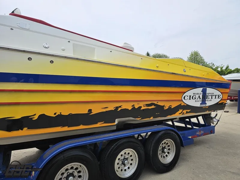 Slide: The Image of 2001 Cigarette 42 Tiger boat with vibrant yellow and blue design on a trailer. - 26