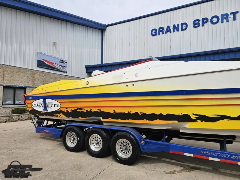 Slide: The Image of 2001 Cigarette 42 Tiger boat with vibrant graphics on a trailer outside Grand Sport facility. - 6