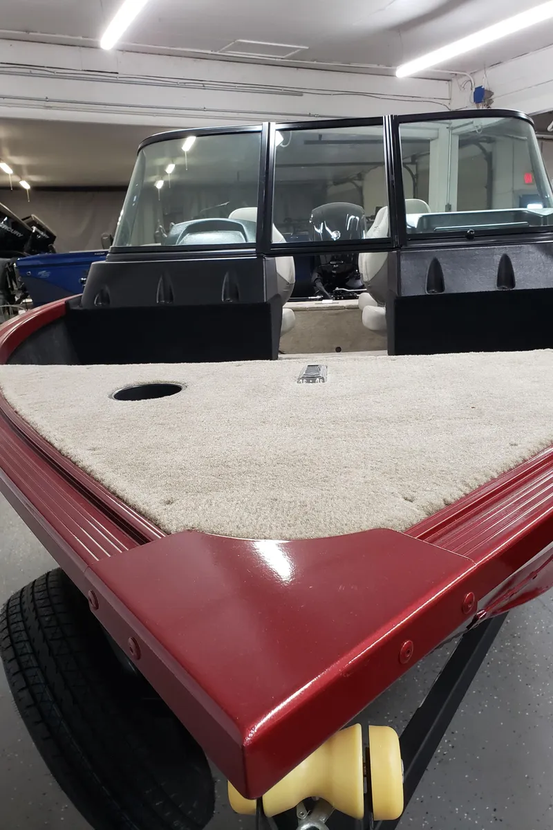 Slide: The Image of 2024 Alumacraft 165 SPT boat with red exterior and spacious interior in a garage setting. - 3