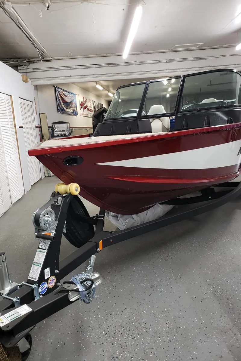 Slide: The Image of 2024 Alumacraft 165 SPT boat in showroom, red and white design, on trailer. - 5