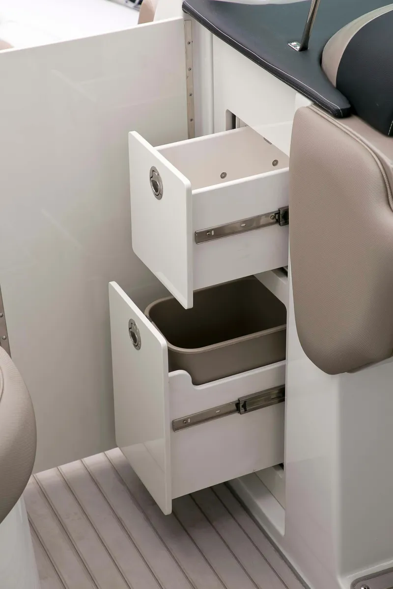 Slide: The Image of 2024 Crownline E305 boat interior with open storage drawers and beige seating. - 18