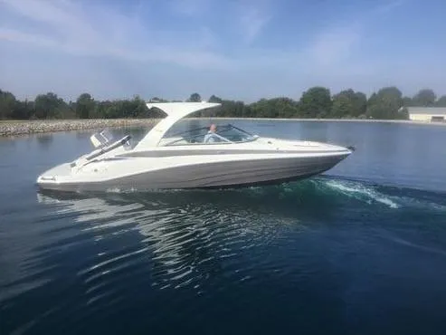 Slide: The Image of 2024 Crownline E305 boat cruising on a calm lake under a clear blue sky. - 3