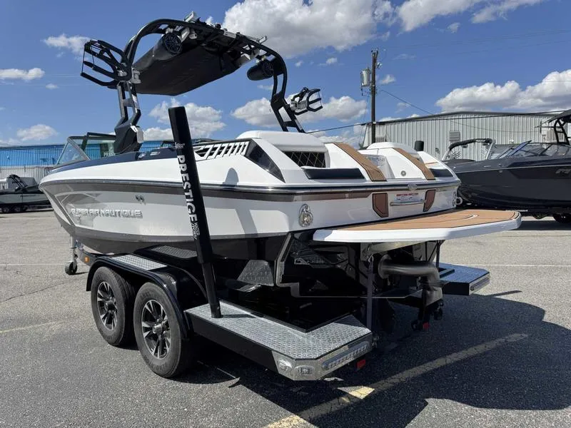 Slide: The Image of 2017 Nautique GS20 boat on trailer, white exterior, wakeboard tower, sunny day. - 10