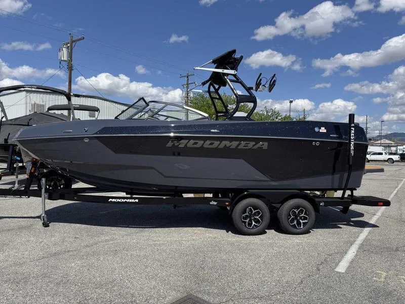 Slide: The Image of 2025 Moomba Max boat on trailer under a clear blue sky. - 0