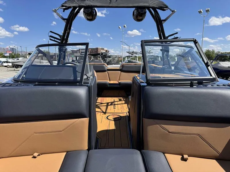 Slide: The Image of 2025 Moomba Max boat interior with black and tan seating, open windshield, and tower speakers. - 13