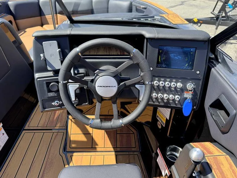 Slide: The Image of 2025 Moomba Max boat dashboard with steering wheel and control panel. - 2