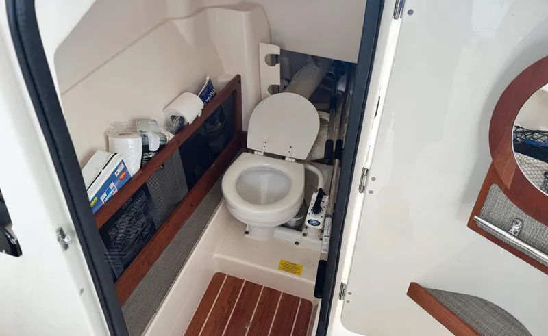Slide: The Image of 2017 Grady-White Freedom 275 boat interior with compact marine toilet and storage shelves. - 9