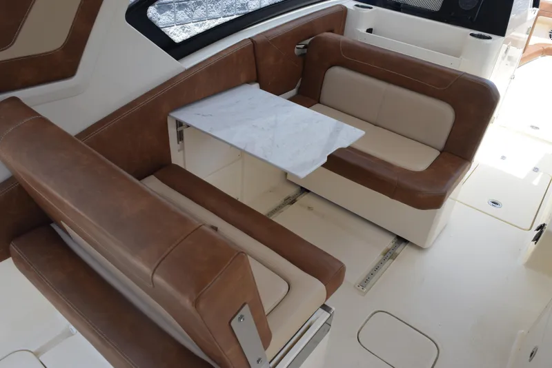 Slide: The Image of 2023 Scout 277 Dorado boat interior with brown leather seating and a foldable table. - 14