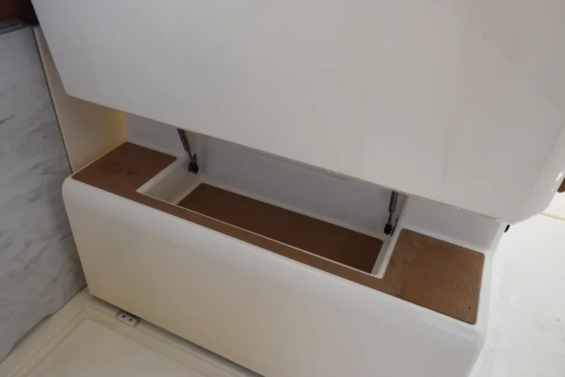 Slide: The Image of 2023 Scout 277 Dorado boat storage compartment with open lid and brown mat. - 24
