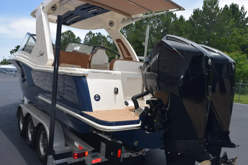 Slide: The Image of 2023 Scout 277 Dorado boat on trailer with dual Mercury engines, parked outdoors. - 5