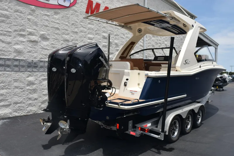 Slide: The Image of 2023 Scout 277 Dorado boat on trailer with dual outboard engines, parked outdoors. - 7
